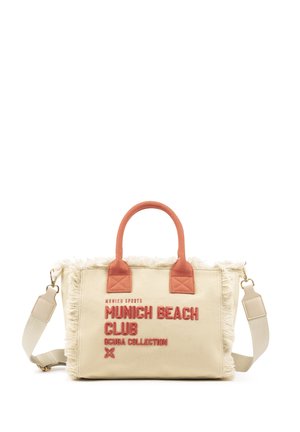 Bolsa tote de lona beige con bordes deshilachados, asas de color óxido y texto rojo que dice "Munich Beach Club Scuba Collection" en el frente.