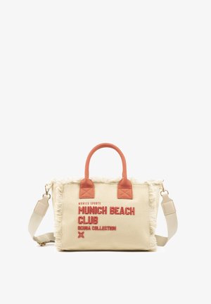 Bolsa tote de lona beige con bordes deshilachados, asas de color óxido y texto rojo que dice "Munich Beach Club Scuba Collection" en el frente.