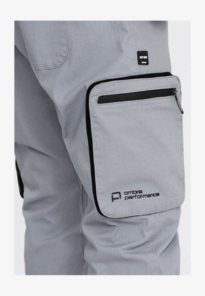 Pantaloni performanti grigi con tasca laterale con zip, hardware nero, texture sottile e dettaglio logo sulla coscia.