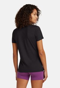 Sort kortærmet t-shirt med blød tekstur, rund halsudskæring og tætsiddende pasform, parret med lilla træningsshorts.