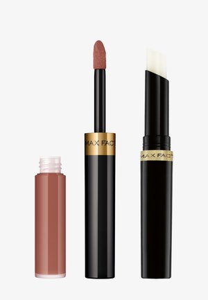 Produits de lèvres Max Factor : un rouge à lèvres liquide nude dans un tube transparent, un tube noir avec un applicateur blanc, tous deux avec des accents dorés.