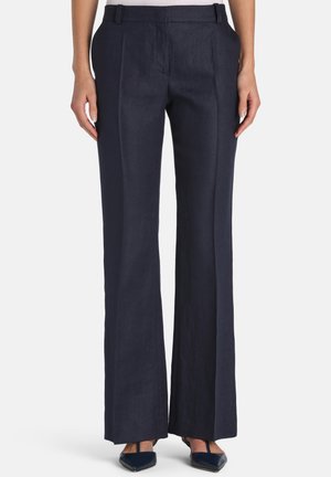 Tengerészkék, széles szárú nadrág elülső hajtásokkal, oldalzsebekkel, övbújtatókkal, fekete, hegyes orrú magassarkú cipővel viselve.