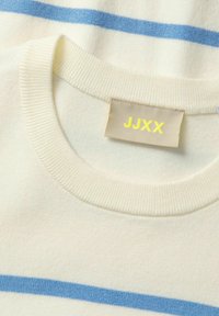 Stribet crewneck sweater lavet af blødt cremefarvet stof med lyseblå vandrette striber. Mærket viser "JJXX" i gul.