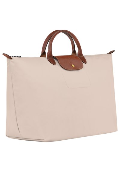 Beige tote bag with smooth fabric, brown textured leather handles, a flap with a gold button, and a spacious design for practical use.