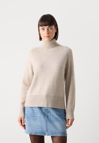 Beige coltrui van zachte wol met geribde zoom en boorden, gecombineerd met een spijkerrok. Eenvoudig, casual ontwerp met een ontspannen pasvorm.