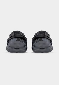 Μαύρα και γκρι σανδάλια Crocs καμουφλάζ με ρυθμιζόμενα λουράκια, εμφανιζόμενα από το μπροστινό μέρος σε απλό γκρι φόντο.