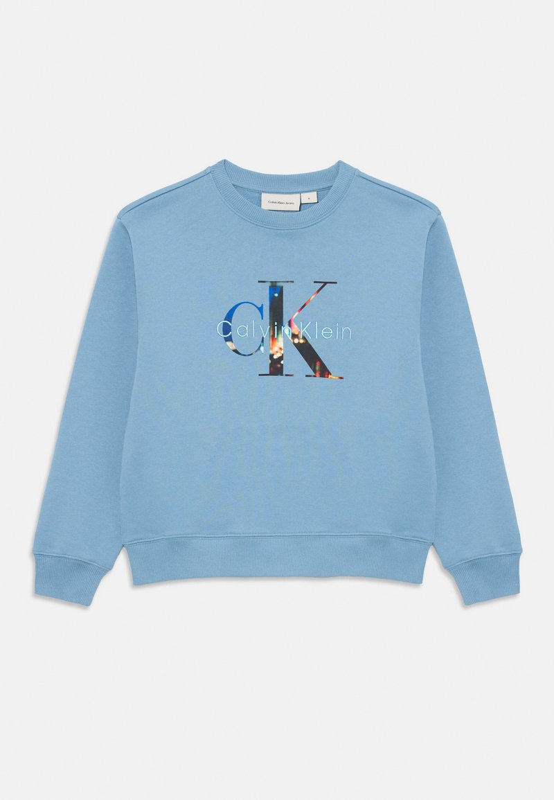 Sweatshirt azul claro de mangas longas com punhos e barra canelados, apresentando um grande logótipo "CK" e "Calvin Klein" com padrão multicolorido na frente.