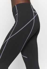 Czarne legginsy z kontrastowym przeszyciem w geometryczny wzór. Wysoki stan z gładkiego, elastycznego materiału dla komfortu i swobody ruchów.