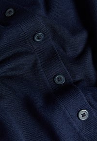 Granatowy sweter z dzianiny z pięcioma ciemnymi guzikami wzdłuż listwy, z miękkiego, teksturowanego materiału oraz żebrowanym wykończeniem.