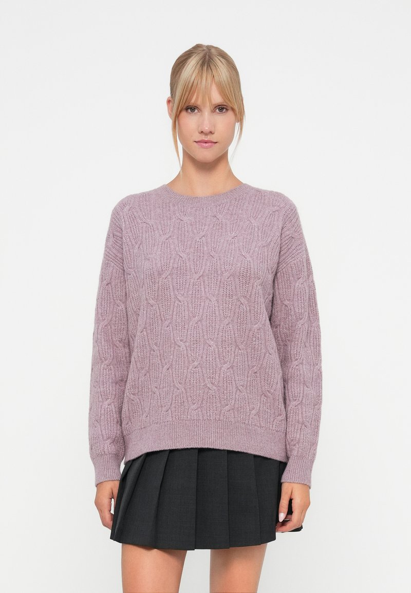 Sweater de malha lilás claro com um padrão de corda texturizado, gola redonda e punhos canelados. Combinado com uma saia pregueada escura.