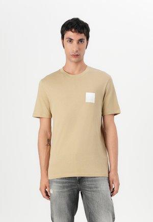Short-sleeve beige t-shirt in soft cotton with a crew neck and a white rectangular patch featuring "HUGO" logo on the left chest.
