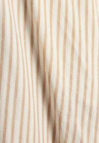 Pruhovaná tkanina v béžovej a bielej farbe, ktorá má tenké, rovnomerne rozmiestnené prúžky. Textúra vyzerá jemne a má mierny lesk.