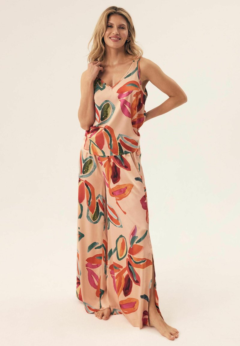 Satinowy zestaw piżamowy w jasnoróżowym kolorze z dużymi, kolorowymi kwiatowymi wzorami. Bluzka z regulowanymi ramiączkami; spodnie luźne, z bocznymi rozcięciami.