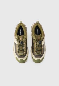 Green and beige athletic shoes with a textured mesh upper, elastic laces, and a rubber sole. Features a pull tab and brand label inside.