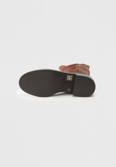 Stivale in suede marrone sdraiato su un lato che mostra una suola in gomma nera con taglia 37 e marchi del brand su sfondo bianco.