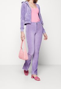 Lavendel velour cropped hoodie, ljusrosa ribbad tank top, randiga lila utsvängda byxor, vävd rosa handväska och rosa slidesandaler.