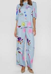 Light blue floral blouse with voluminous sleeves paired with matching wide-leg trousers. Features vibrant multi-colored floral patterns.