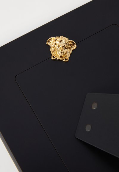 Μαύρος φάκελος με χρυσό έμβλημα της Μέδουσας, με λεία υφή και οργανωμένο σχεδιασμό. Περιλαμβάνει κλείσιμο με πτυσσόμενο καπάκι και δύο μεταλλικές λεπτομέρειες.