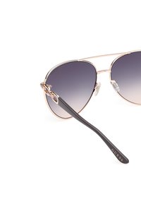 Pilotglasögon med gradientgrå linser, ram i roséguldmetal och svarta plastbågar, med en dekorativ hårdvarudetalj.