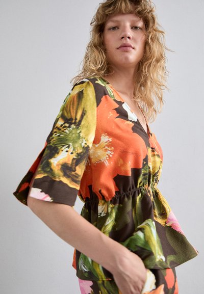 Top floral cu nuanțe de portocaliu, verde și brown. Mâneci scurte evazate, decolteu în formă de V și detalii cu talie elastică formează o siluetă peplum.