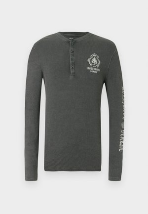 Dlhý rukáv henley tričko v tmavošedej vaflovanej pletenine, s gombíkovou légou a grafickým potlačou na hrudi a rukáve.