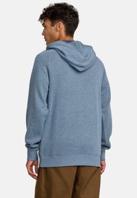 Light blue ribbed hoodie with a large hood, long sleeves, and a relaxed fit. Notable details include ribbed cuffs and hem.
