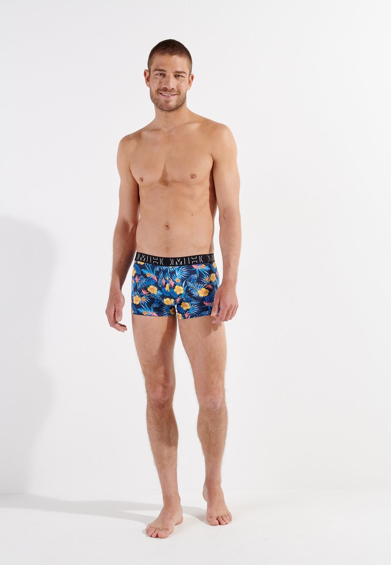 Boxer ajustados para hombres en un colorido patrón floral que presenta azul, amarillo y verde. Cintura elástica negra con logo. Tejido suave y elástico.