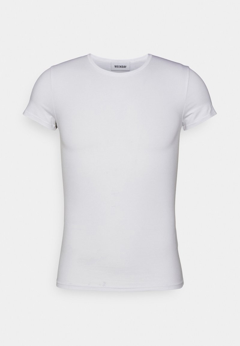 T-shirt blanc à manches courtes et col rond, coupe ajustée, présenté sur un fond gris clair uni.