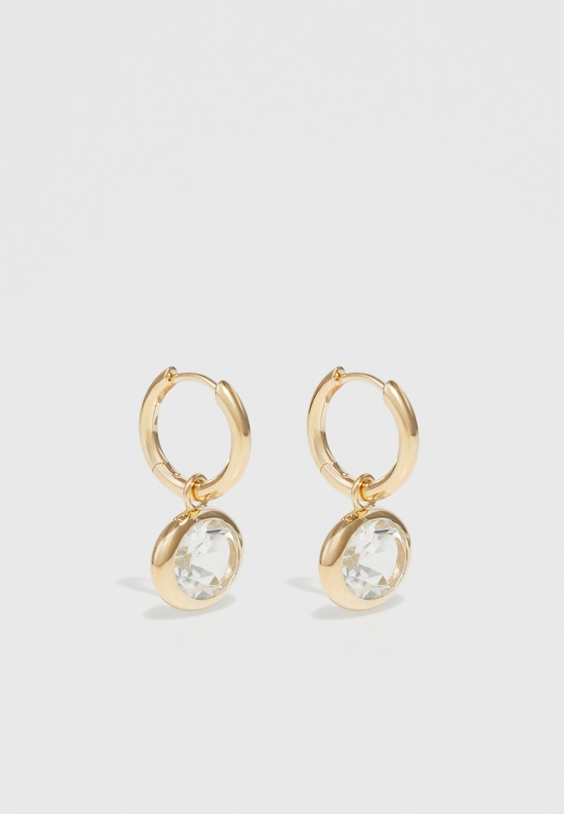 Cercei din aur în formă de cerc, cu un pandantiv din cristal transparent, de formă rotundă, cu textură netedă și un finisaj lustruit.