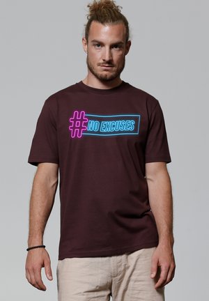 Burgunderrotes Baumwoll-T-Shirt mit einem neonblauen und pinken Grafikdesign, das den Text "#NO EXCUSES" mittig auf der Vorderseite enthält. Kurze Ärmel, Rundhalsausschnitt.