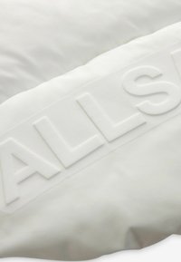 Vit kudde med präglad text "ALLSTAR", med en smidig tygtextur och rektangulär form, som har en ren, minimalistisk design.