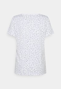 Camisa blanca de manga corta con un patrón floral en azul y negro. Material suave, corte relajado, escote redondo, vista trasera mostrada.