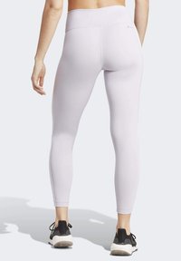 Lichtpaarse sportleggings met een hoge taille en een gladde textuur. Heeft een strakke pasvorm en contrasterende stiksels. Draag samen met zwarte sneakers.
