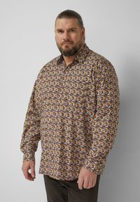 Koszula na guziki z długim rękawem, z wielobarwnym geometrycznym wzorem na brązowym tle. Posiada klasyczny kołnierzyk i mankiety na rękawach.