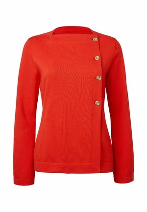 Punainen neulepaita, jossa on neliönmuotoinen pääntie, pitkät hihat ja sivunappikiinnitys kultasävyisillä napilla korostuksena.