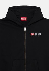 Black zip-up hoodie made of smooth fabric, featuring a large red "DIESEL" logo and a small zippered front pocket.