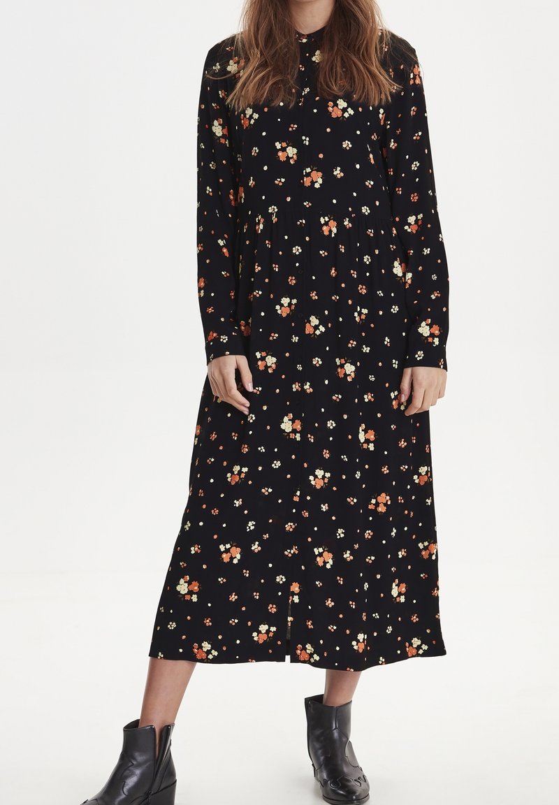 Abito nero floreale con maniche lunghe, colletto abbottonato e un motivo di fiori arancioni e bianchi con un design a strati.