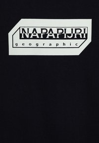 Tessuto nero con un design grafico contenente "NAPAPIJRI" in lettere maiuscole sopra la parola "geographic". Il testo è incorniciato da un contorno rettangolare bianco.