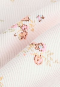 Floral-patterned fabric in soft pink, featuring ribbed texture with small blooms in pastel colors of pink, blue, and brown.