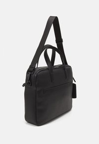 Schwarze Lederhandtasche mit rechteckiger Form, verstellbarem Träger, zwei Griffen oben und einer Vordertasche mit flacher Akzentuierung.
