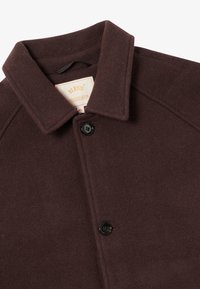 Brown wool coat with a structured collar, featuring a single button closure and a soft, textured fabric. Label visible inside.