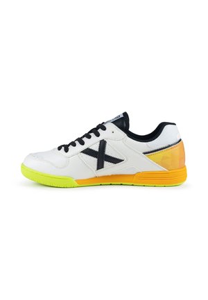 Chaussure de sport blanche avec lacets noirs, logo latéral noir, semelle avant vert néon et accents orange au talon et à la semelle intermédiaire.