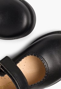 Zapatos Mary Jane de cuero negro con punta redondeada, abertura ondulada y tiras de Velcro. Superficie lisa con plantilla de cuero color tostado.