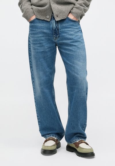 Világoskék, laza szabású farmernadrág. Klasszikus öt zsebes kialakítással rendelkezik, finom kopásokkal és egyenes szárú fazonban.