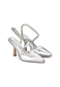 Tacchi slingback in raso argento con punta affusolata, tacco basso e una fascia decorata di gioielli. Presentano una texture liscia e un design minimalista.