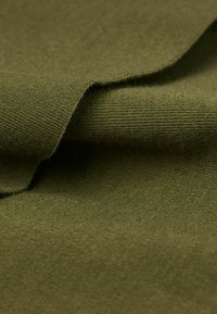 Olivově zelená látka, pletená textura, měkká, s mírně chlupatým povrchem, prezentující překrývající se vrstvy.