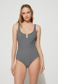 Černobílý kostkovaný jednodílný plavky s širokými ramínky, kulatým výstřihem a výřezem ve tvaru klíčové dírky vpředu. Hladká textura látky.