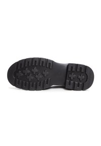 Semelle de chaussure noire avec des crampons profonds incluant des motifs rectangulaires et en forme de croix pour l'adhérence et la durabilité.