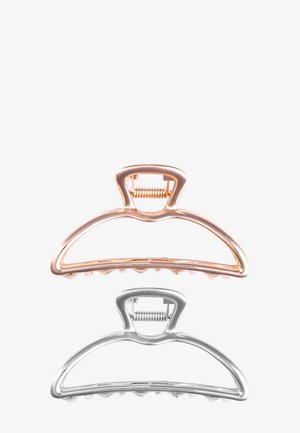 Deux pinces à cheveux en métal, une en or rose et une en argent, avec un fermoir à ressort et des dents arrondies sur un fond blanc uni.