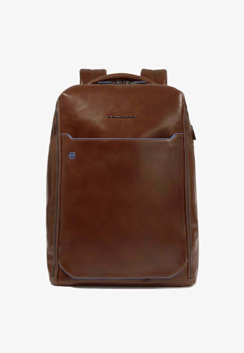 Mochila de cuero marrón con una textura suave, que presenta costuras de acento azules, un bolsillo delantero con cremallera y dos correas para los hombros.